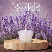SerrBeauty Lavendel & Patchouli Bienenwachs Duftkerze 125 g in einem eleganten Glasbehälter, umgeben von blühendem Lavendel. Die biologische Bienenwachskerze sorgt für eine beruhigende Atmosphäre mit natürlichen ätherischen Ölen.